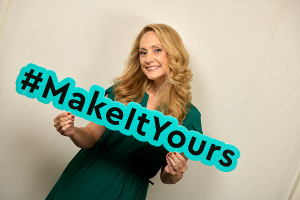 Amy posing with a sign that says Make It Yours