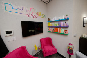 one wall of their suite with a tv and shelves displaying hair product