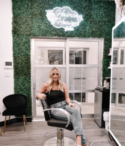 woman sitting in chair in her my salon suite with green wall
