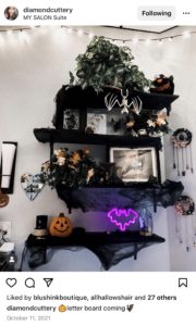 picture of shelves in salon decorated with black halloween decor including bats and pumpkins