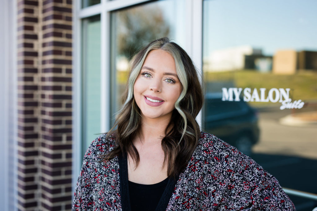 A Suite Elite Member standing in front of a MY SALON Suite front door